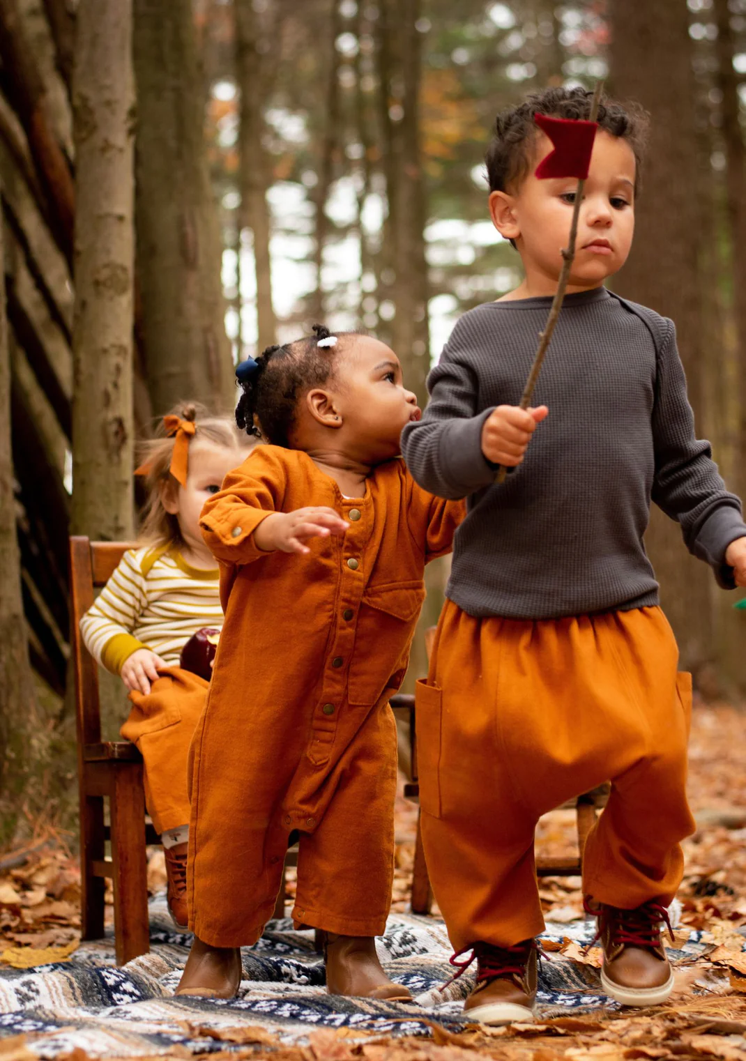 Three toddlers wearing West Rock Apparel in a forest setting.